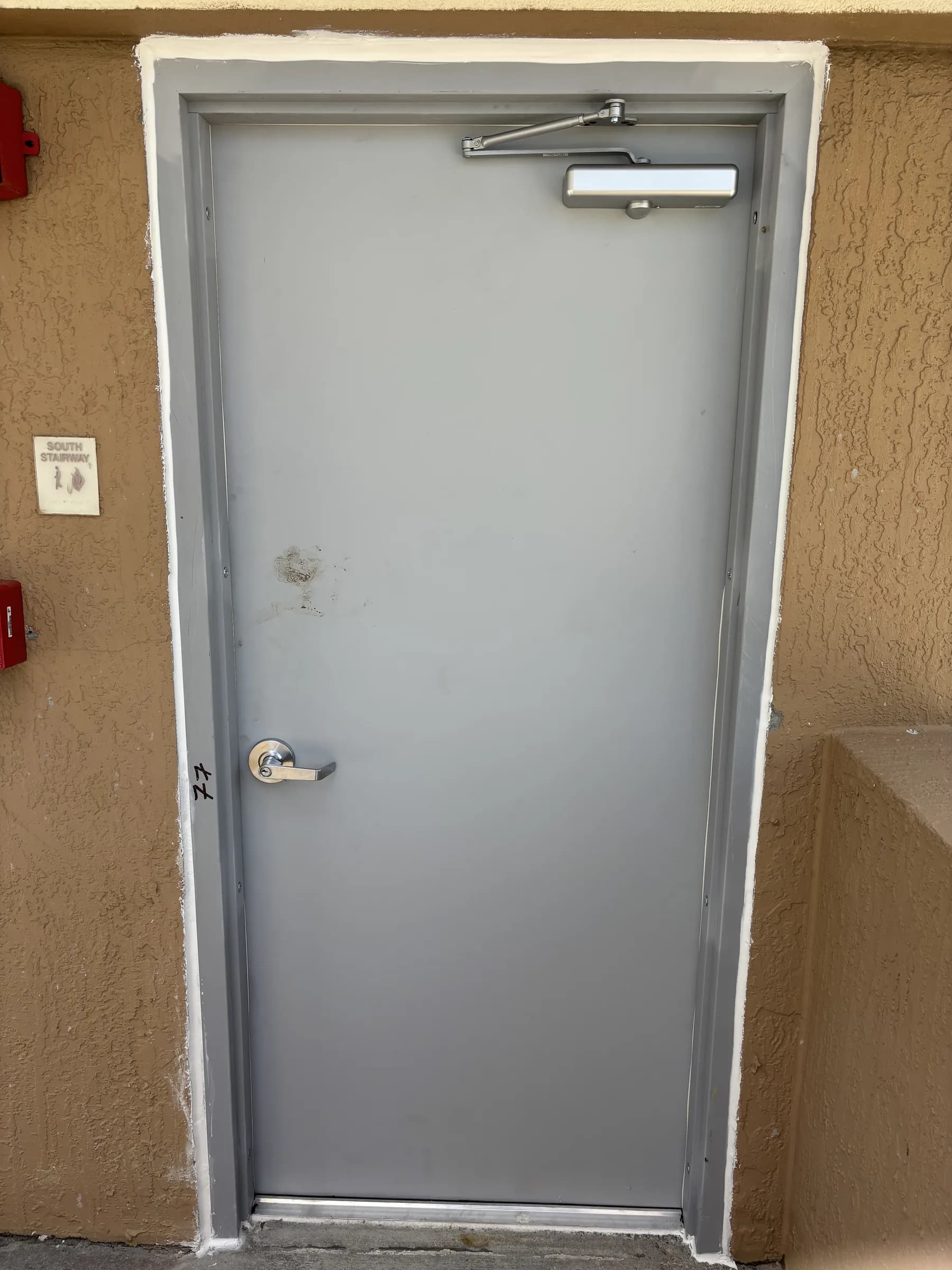 Commercial fire door at a south stairway exit with automatic closer and lever hardware
