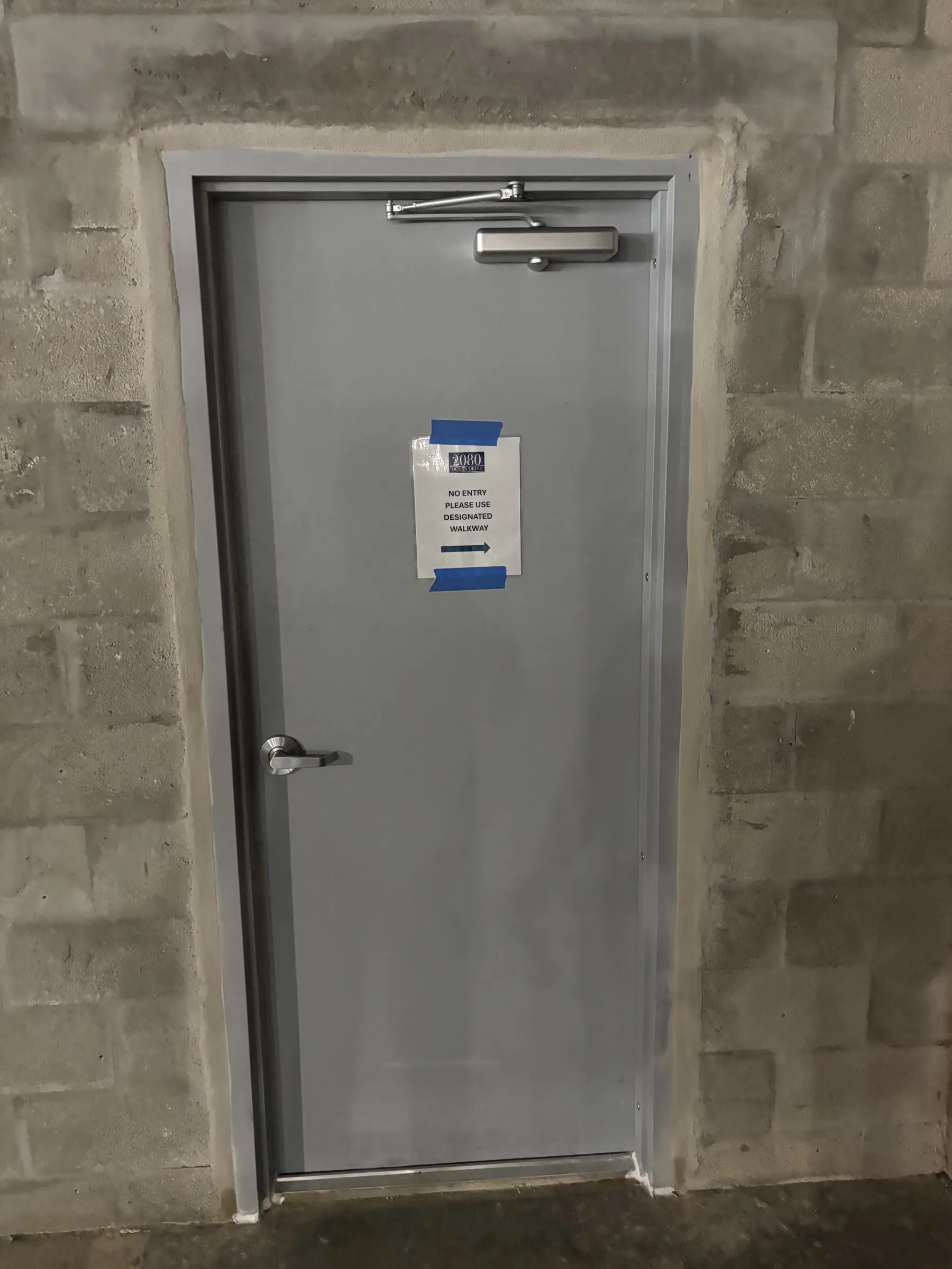 Gray fire-rated hollow metal exit door with panic bar installed in a concrete block wall