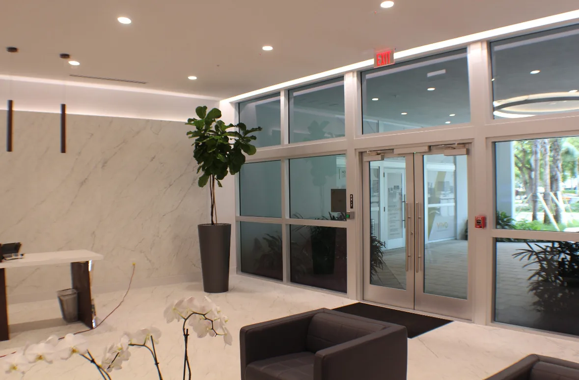 White aluminum storefront double glass doors in a commercial lobby with exit sign above