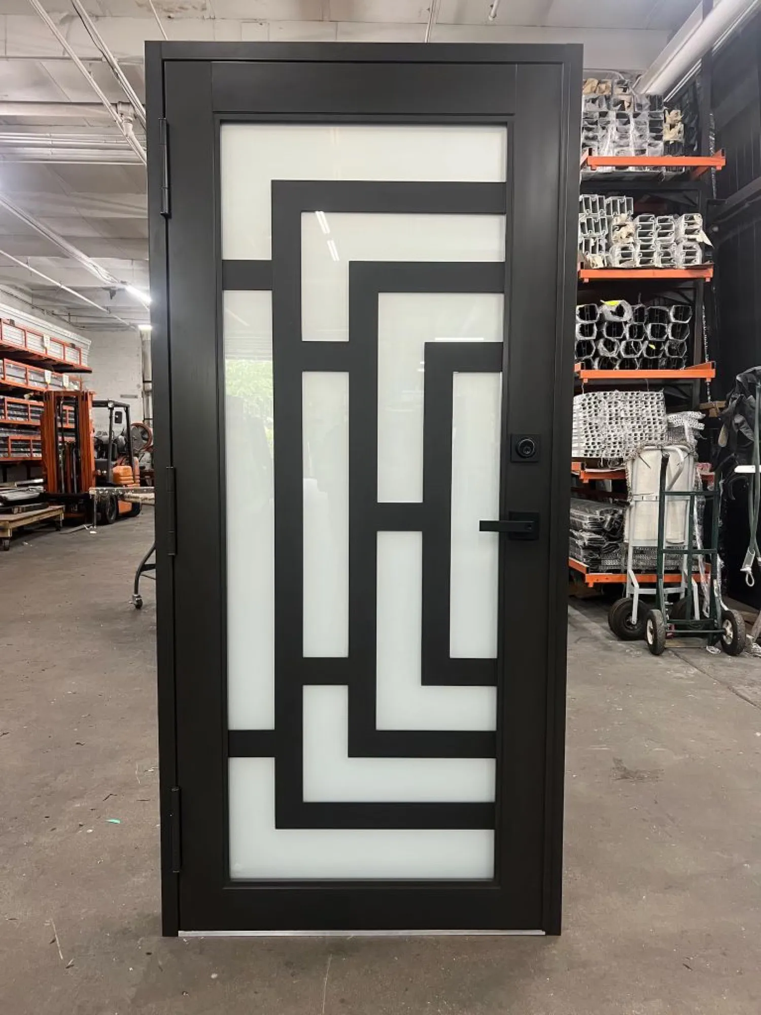 Black entry door with geometric frosted glass pattern in a warehouse