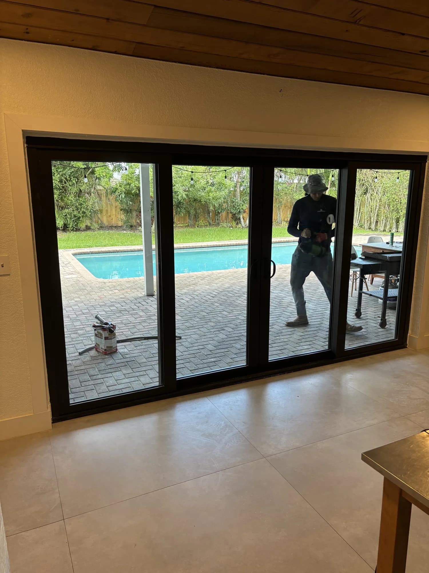 Four-panel sliding glass door opening to a backyard pool and patio