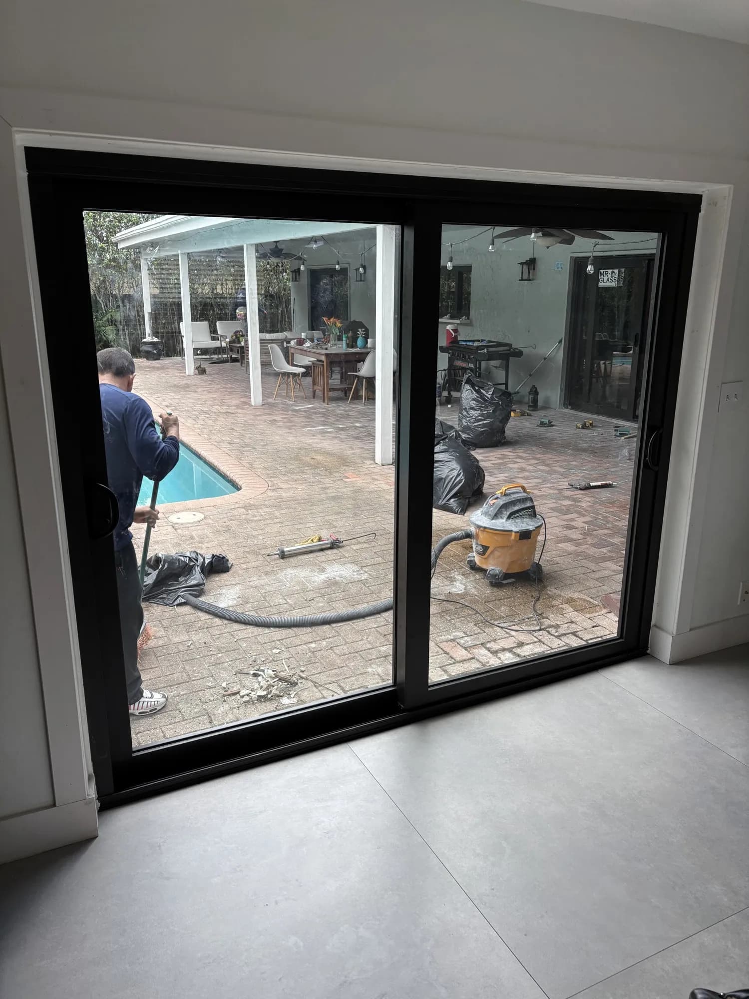 Interior view of a black sliding patio door while an installer finishes work outside