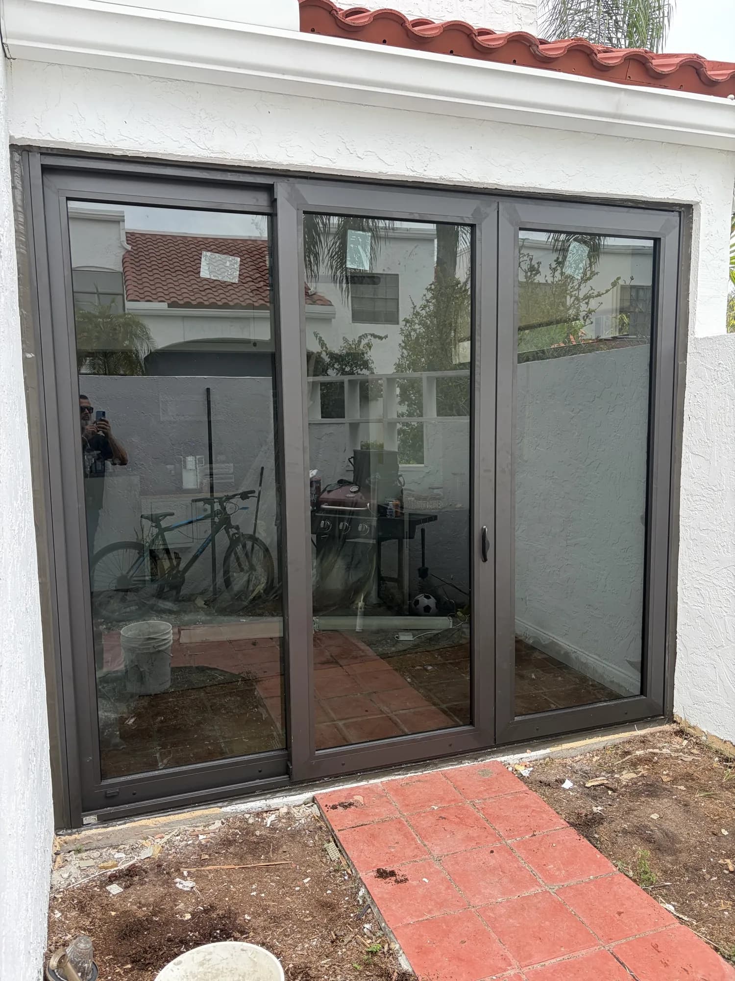 Three-panel sliding glass door system on a white stucco patio wall