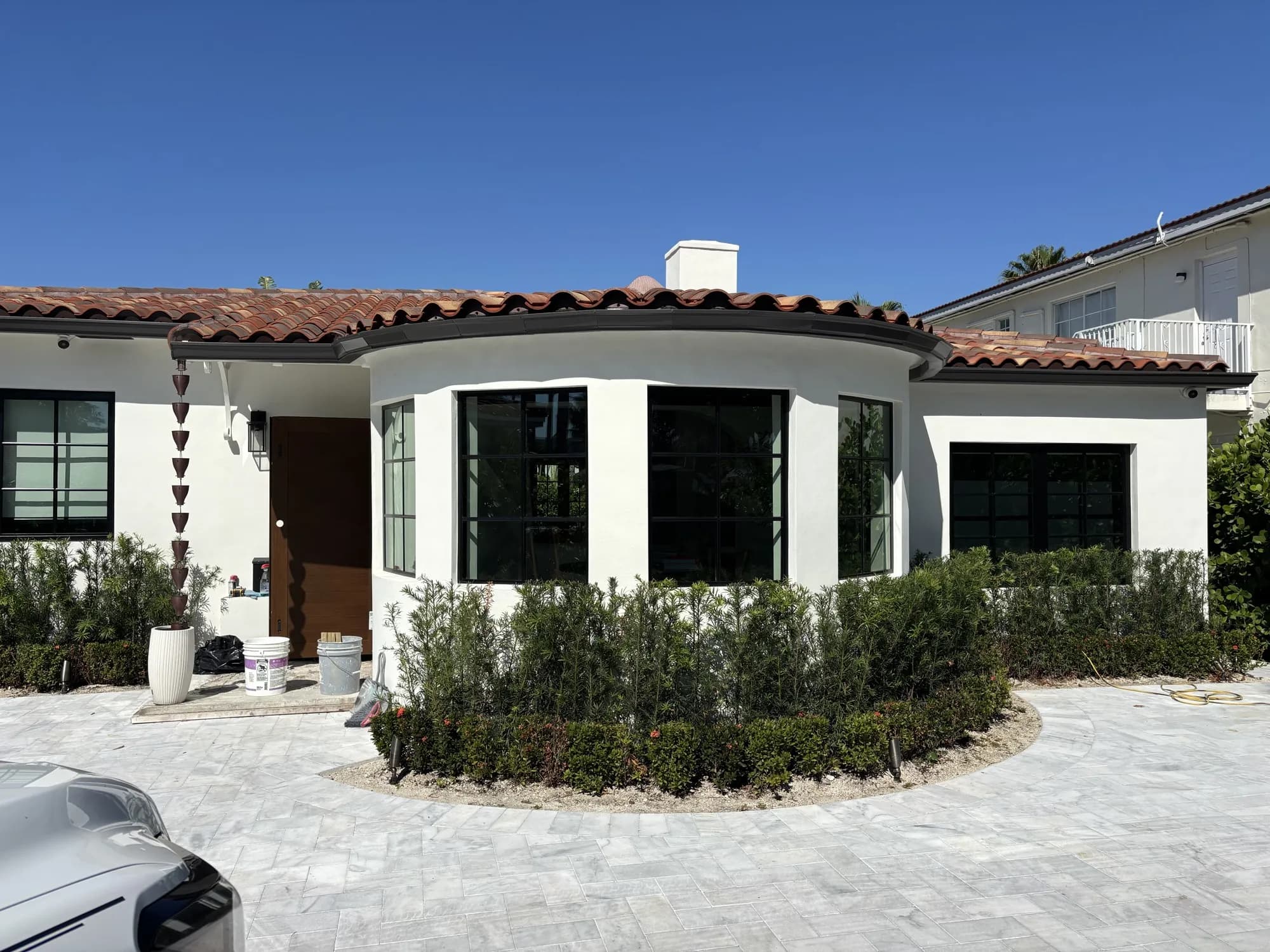 Front facade with curved black-grid windows, entry door, and landscaped pavers
