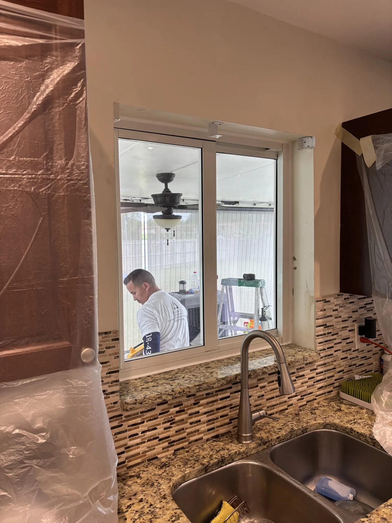 Kitchen window above the sink with an Atlantic Door Systems installer working outside