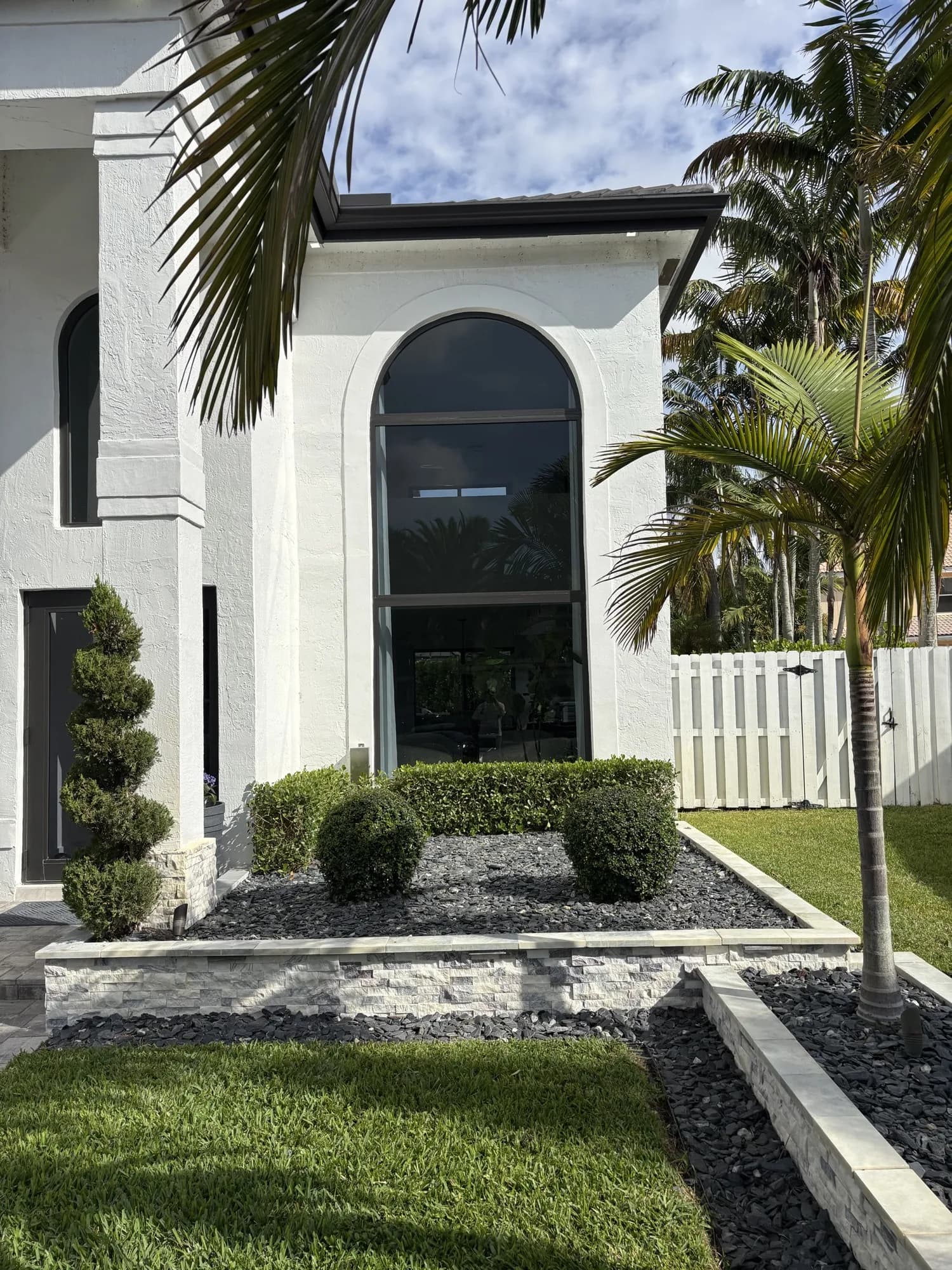 Large black-framed arched window on a modern white stucco house