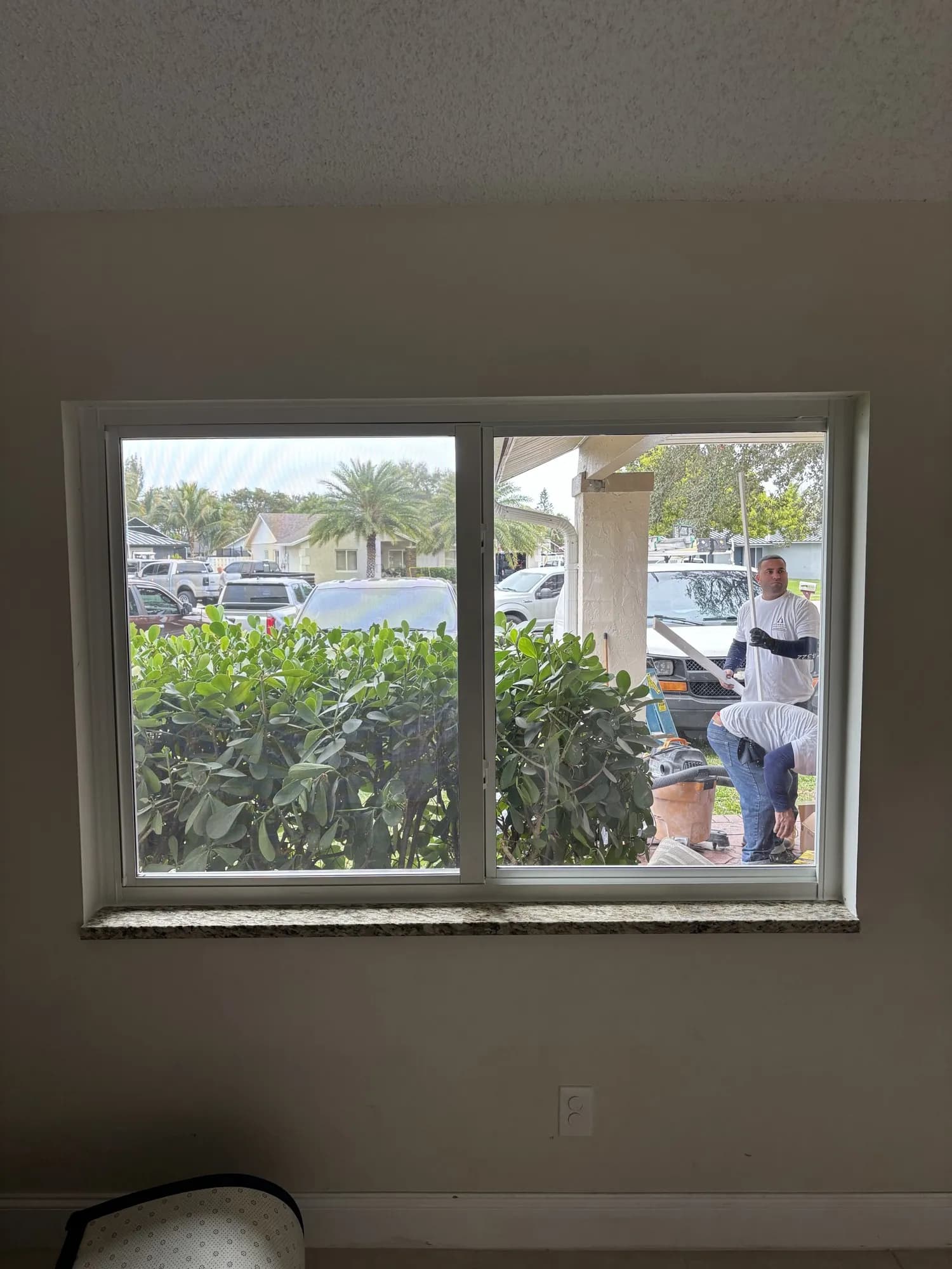 New horizontal sliding window with installation crew working on the covered porch outside
