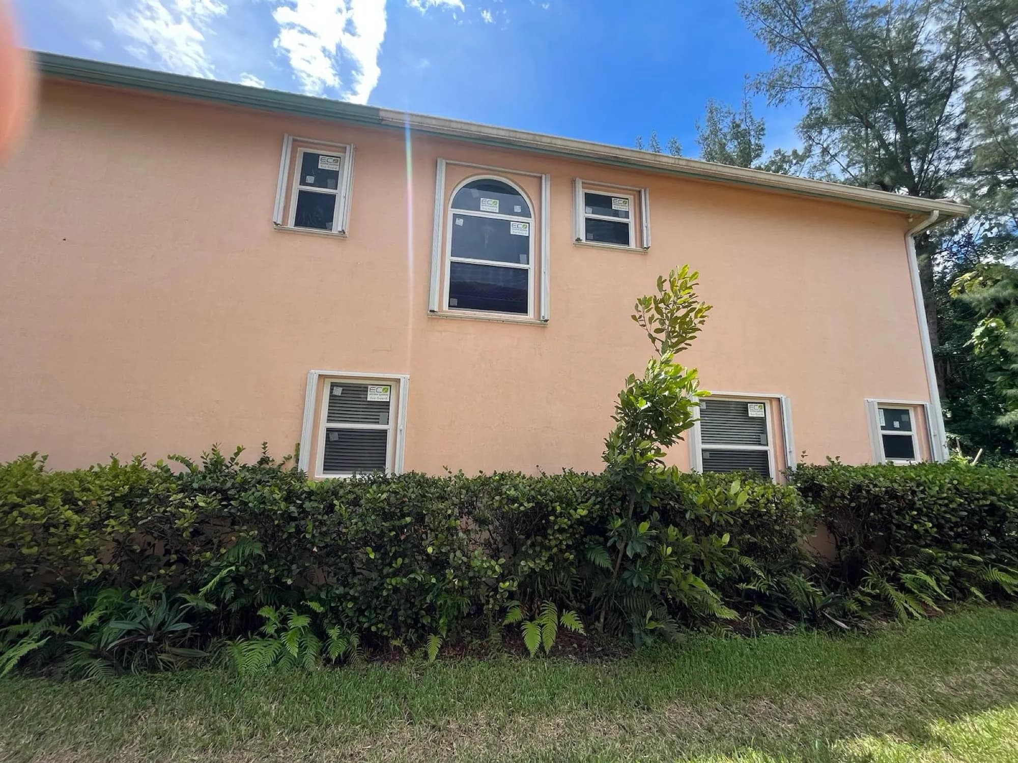 Newly installed white impact windows including a large arched unit on a peach stucco home