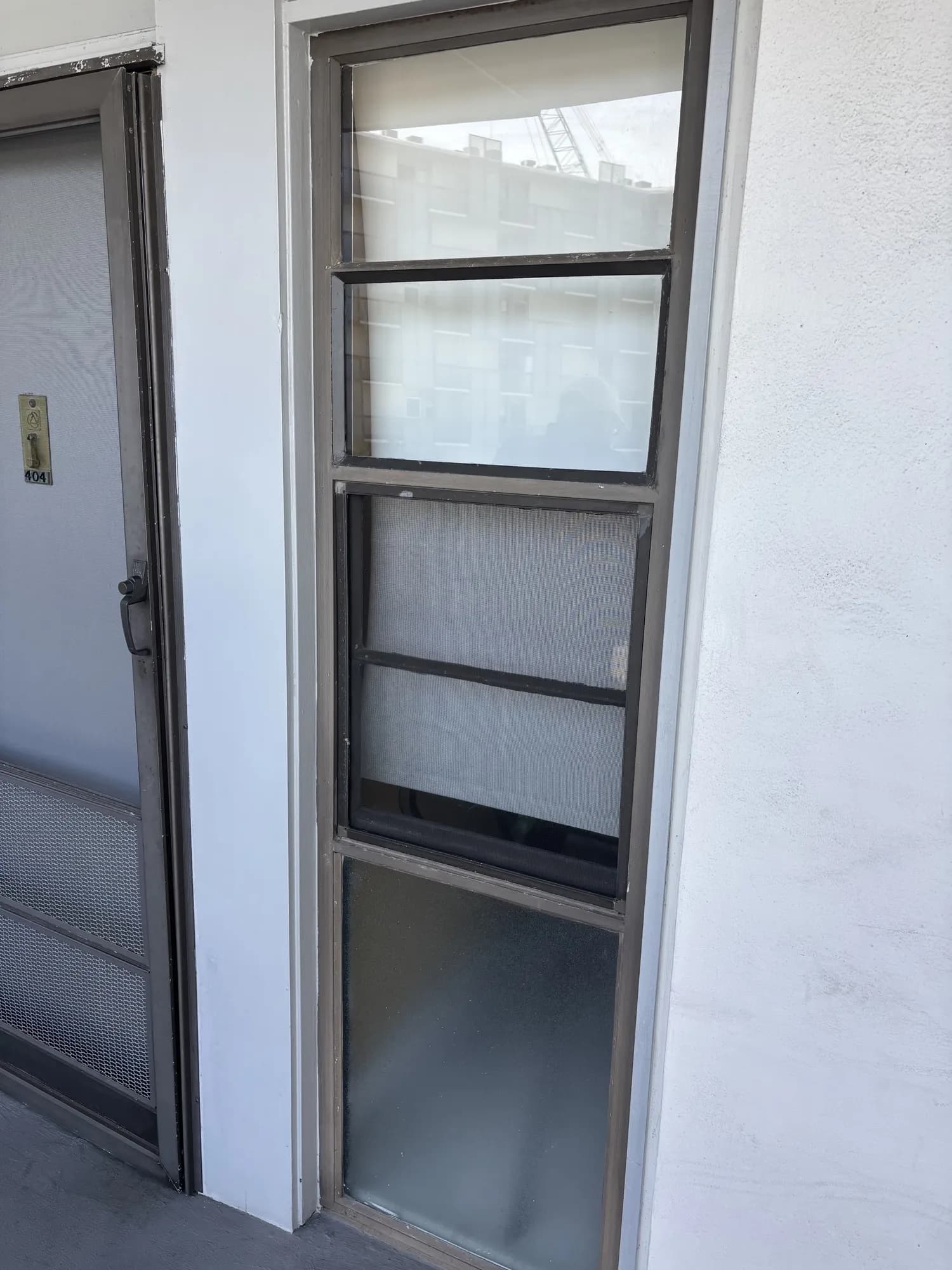 Tall three-section window beside a condo entry door numbered 404