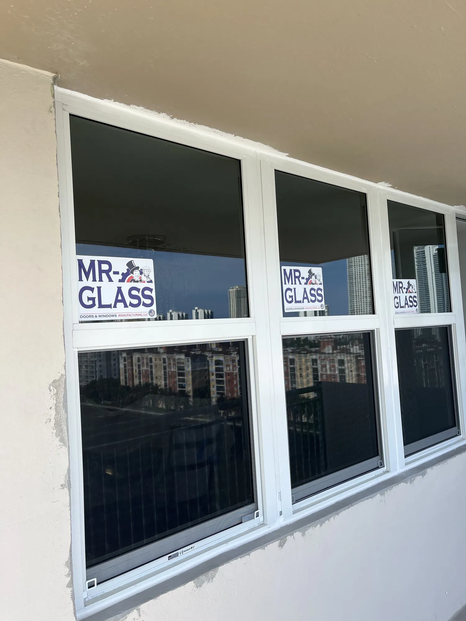 Three newly installed white-framed window units reflecting a downtown skyline